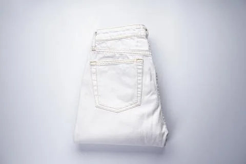 White folded denim pants, back pocket, flat lay. Stock Photos