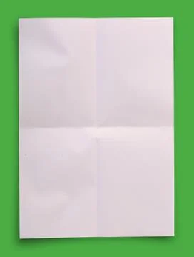 White folded paper on green background, clipping path. Stock Photos