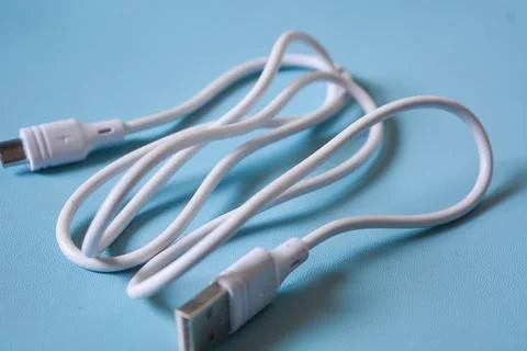 White folded usb and micro usb cable on blue background. Stock Photos