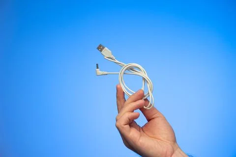 White folded USB charging cable held in hand by Caucasian male hand studio sh 库存照片