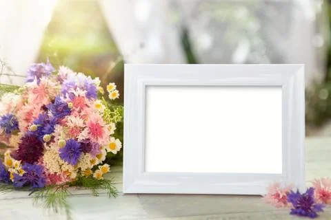 White frame and flowers on table Stock Photos
