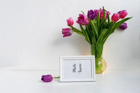 White frame mock up and dry twigs in vase on book shelf or desk. White colors. Stock Photos