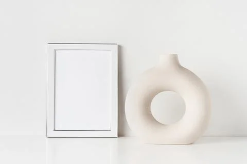 White frame mockup and ceramic vase on a white table by the wall. Copy space for Foto stock