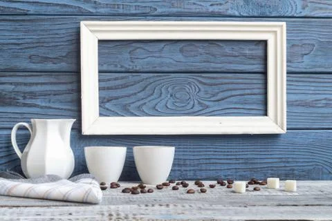 White frame, two coffee cups and a jug on a background of blue b 写真素材