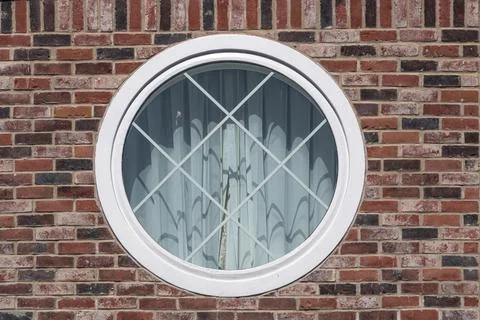 White framed circular window set in a red brick wall Stock Photos