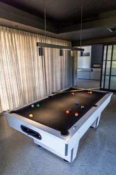 White-framed pool table sitting in modern game room, black felt showing Foto stock