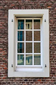 White framed window set in historic brick wall with architectural reflections Stock-Fotos