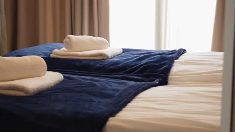 A white fresh and clean folded towels on a hotel room bed in lit with sun light Stock Footage 248529523