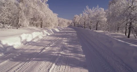 White frozen and snow-covered road in the middle of the forest Stock Footage 104476653