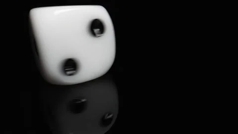 A White Game Dice Spinning on One Spot on a Black Table and a Black Background Stock Footage 204770775