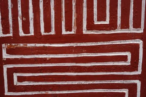 White geometric labyrinth pattern painted on a weathered textured reddish-brown Fotos Stock