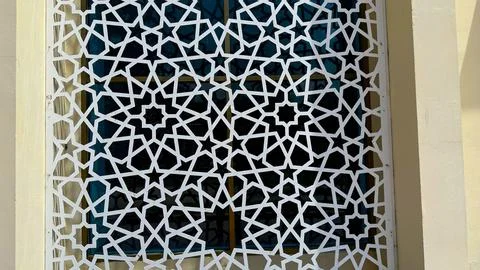 White geometric star pattern creates a decorative lattice screen over a windo Foto stock