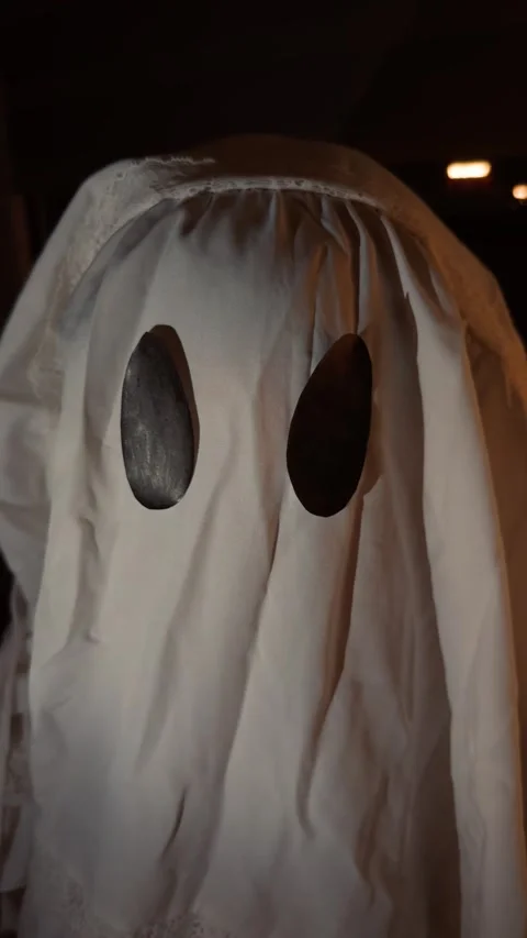 White ghost decoration hangs in shadowy light, adding Halloween decor with Stockbeeldmateriaal 347218273