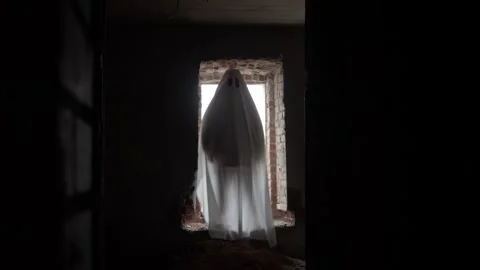 White ghost figure appears in opening of ruined window, draped in flowing sheet Stock Footage 320246619
