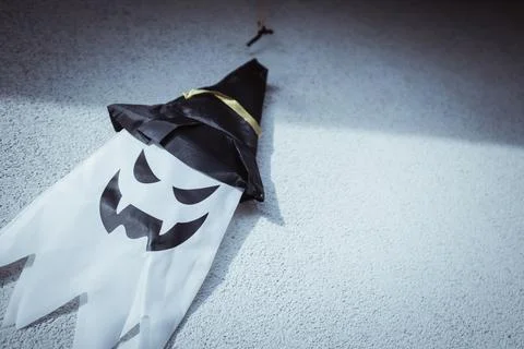 A white ghost with a spooky face and a black witch hat hangs. Stock Photos