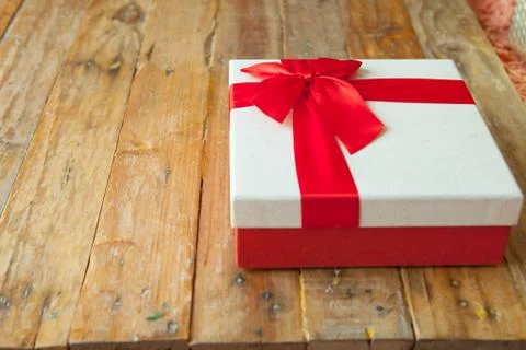 White gift box and red ribbon  on wood background with space.. Stock Photos