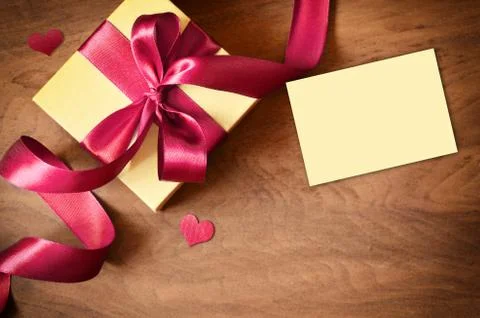 White gift box and red ribbon with tag on wood background. Vintage gift box o Stock Photos