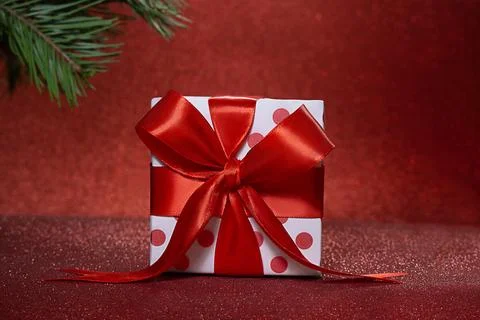 White gift box with dots and bow, spruce branch at back against blurred spa.. Stock Photos