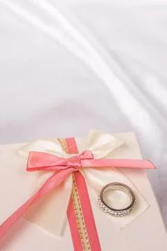 White gift box with red bow and golden wedding ring Foto stock