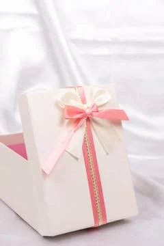 White gift box with red bow over white satin Stock Photos