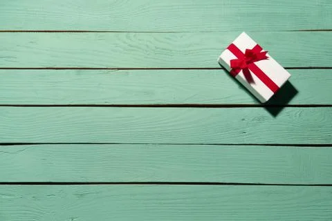 White gift box with red bow on green wooden planks 스톡 사진