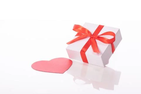 White gift box with red bow and cardboard heart isolated on white background Stock Photos