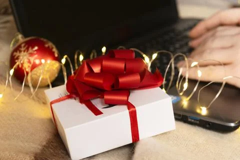 White gift box with red bow and laptop with christmas light Stock Photos