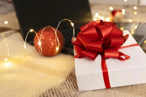 White gift box with red bow and laptop with christmas light Stock Photos