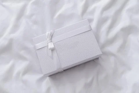 White gift box with ribbon on white bed sheets background Stock Photos