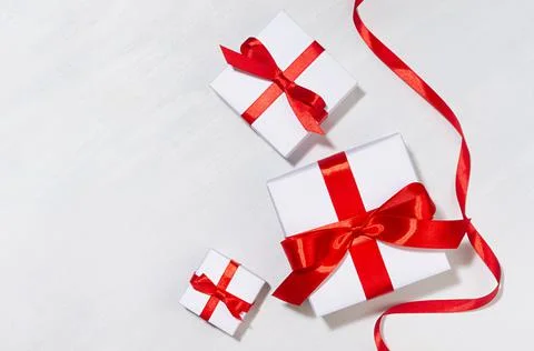 White gift different size boxes with red silk bow, ribbon on white wood table Stock Photos