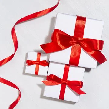 White gift different size boxes with red silk bow, ribbon on white wood table Stock Photos
