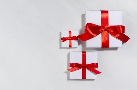 White gift different size boxes with red silk bow, ribbon on white wood table Stock Photos