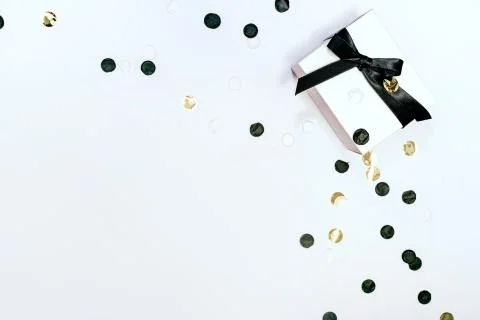 White gift or present box with black ribbon and confetti on white background. Stock Photos