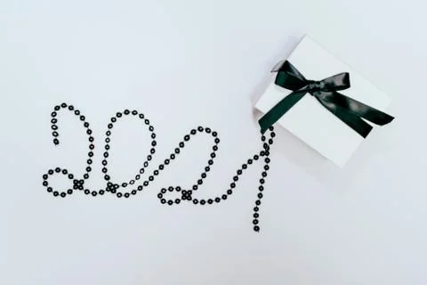 White gift or present box with black ribbon and 2021 number made of beads on Stock Photos