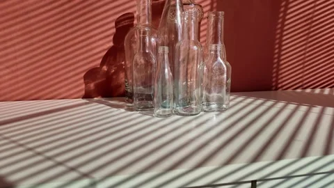 White glass empty bottles are on a table  , illuminated by the sun Stock Footage 303929342