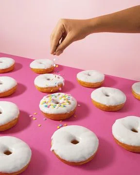 White Glazed Donuts Pattern with Falling Colorful Sprinkles Foto stock