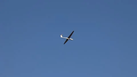 A white glider soars through a clear blue sky, gracefully gliding Stock-Footage 305711385