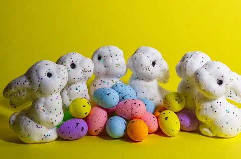 White glitter Easter bunnies and colorful speckled eggs on a bright yellow .. Foto stock