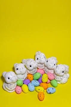 White glitter Easter bunnies and colorful speckled eggs on a bright yellow .. Fotos Stock