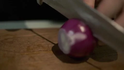 A white-gloved chef cuts red onions with a knife on a cutting board Stock Footage 243343142