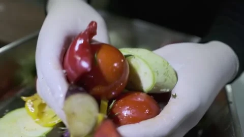 A white-gloved chef stirs vegetables cut into pieces in a container with his Stock Footage 248339260