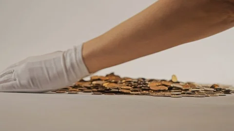 White-gloved hands scooping up a pile of gold coins. They sort out and scatter Stock Footage 122703495