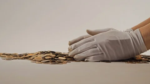 White-gloved hands scooping up a pile of gold coins. They sort out and scatter Stock Footage 122704426