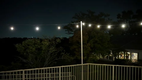 White glowing string light hanging outdoors at night, creating cozy atmosphere Stock Footage 318049389