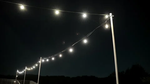 White glowing string lights hanging outdoors at night, creating cozy atmosphere Stock Footage 317733643