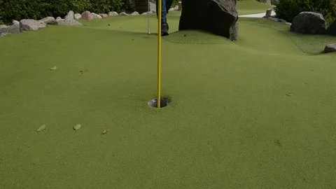 White golf ball rolling past a hole Stock Footage 273250776