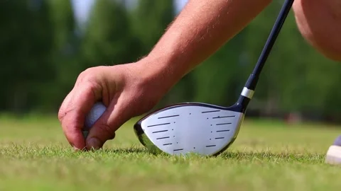 White golf ball on a stand on a green field, putter on the background Video stock 166593489