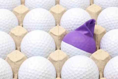 White golf balls in the box for eggs. Golf ball with funny cap. 스톡 사진