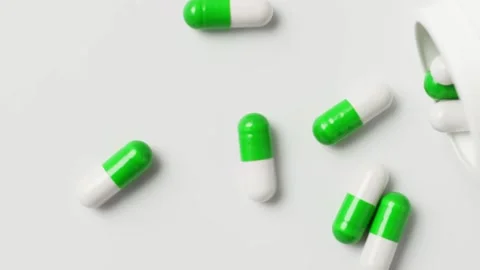White-green capsules fall out of the bottle onto the table, top view. Stock Footage 147582594