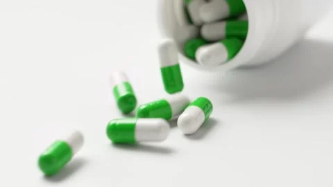 White-green capsules fall out of the bottle onto the table, slow motion. Stock Footage 147582598